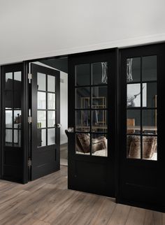 an empty room with black doors and wooden floors