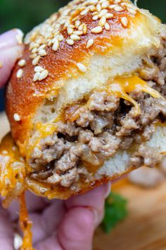 a hand holding a hamburger with cheese and meat