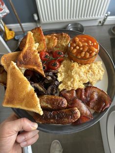 a plate full of breakfast food with beans, bacon, toast and other foods on it