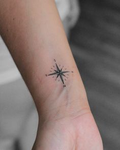 a small compass tattoo on the wrist is shown in black and white, as well as an arrow