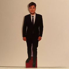 a cardboard cutout of a man in a suit and tie standing next to a wall