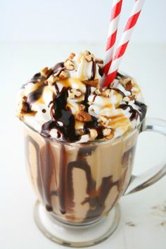 a chocolate milkshake with whipped cream, nuts and candy on top in a glass mug