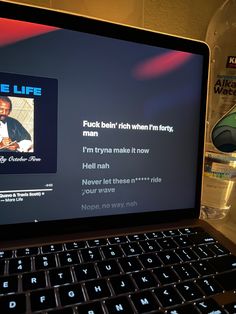 an open laptop computer sitting on top of a desk next to a bottle of water