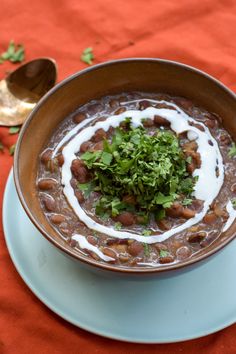 a bowl filled with beans and sour cream on top of a blue plate next to spoons