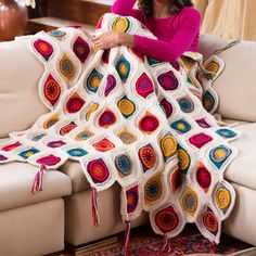 a woman sitting on a couch holding a crocheted blanket