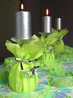 two green vases with silver candles in them on a table covered with polka dots