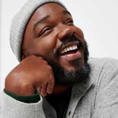 a close up of a person wearing a beanie and holding his hand to his ear