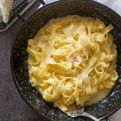 a skillet filled with pasta on top of a table