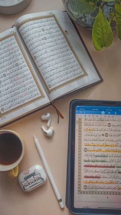 an open book sitting on top of a table next to a cup of coffee and headphones