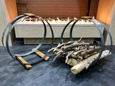 a fire pit made out of logs and metal rings on the floor next to a fireplace