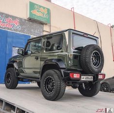 a green jeep parked in front of a building