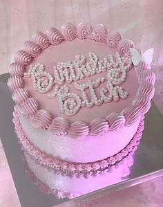 a pink birthday cake sitting on top of a glass plate with the words happy bling