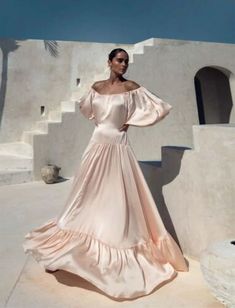 a woman in a long dress standing on the steps wearing an off - shoulder gown