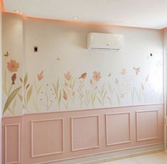 an air conditioner mounted to the side of a wall with flowers painted on it