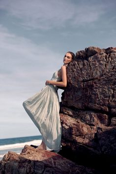 a woman standing on top of a rock near the ocean