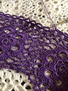 crocheted purple doily sitting on top of a piece of white knitted material