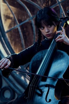 a woman with black hair holding a cello