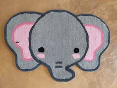 an elephant rug with pink ears on it's head is shown in front of a brown wall