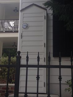 a tall white building with a clock on it's face and black iron fence