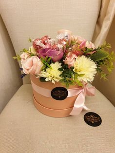 a pink and white flower pot sitting on top of a chair next to a sticker