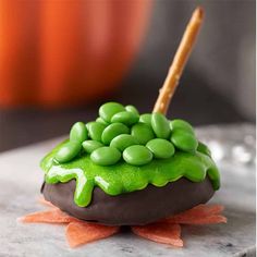 a cake with green icing on top of it sitting on a table next to a pumpkin