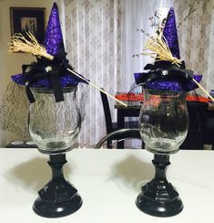 two glass vases with purple hats on them