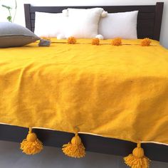 a bed with yellow blankets and pillows on it's headboard, along with two throw pillows