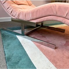 a pink chair sitting on top of a rug next to a metal frame footstool