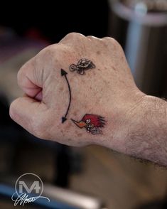 a man's left hand with an arrow and bird tattoo on the middle finger