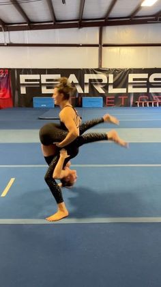 two women are doing acrobatic exercises on a blue floor in an indoor gym