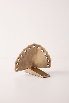 a metal object sitting on top of a white table next to a wooden block with holes in it