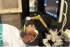 a man laying in a hospital bed looking at a computer screen with an eyepiece on it