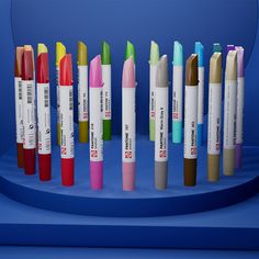 many different colored pens are lined up on a blue display stand against a blue background