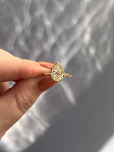 a woman's hand holding a yellow diamond ring