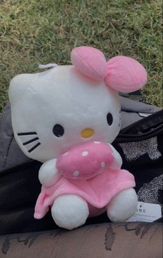 a hello kitty stuffed animal sitting on top of a black bag next to a backpack