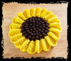 a crocheted sunflower sitting on top of a wooden table