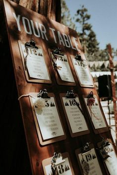 a wooden table with seating cards attached to the back of it's sides and hanging from chains