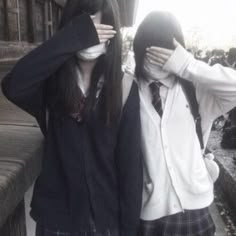 two young women standing next to each other with their hands covering their faces and looking at the camera