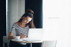 a woman sitting at a table working on her laptop