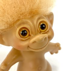 a close up of a toy troll with big eyes and blonde hair on it's head