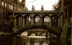 a bridge over a body of water with buildings on either side and people walking under it