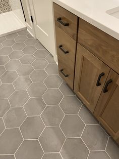 a bathroom with hexagonal tile flooring and wooden cabinets