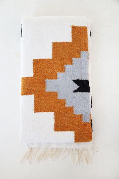 an orange and white rug with fringes on the bottom is sitting on a table