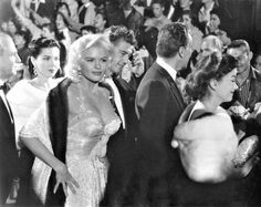 black and white photograph of marilyn monroe at an event with other people in the background