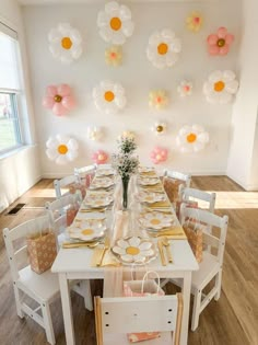 a dining room table set with place settings and flowers on the wall