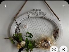 a chicken wire wreath hanging on a wall with flowers and other things in it's center