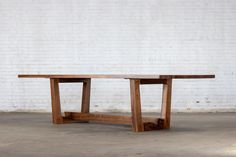 a wooden table sitting on top of a cement floor next to a white brick wall