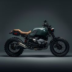 a green motorcycle parked on top of a black floor next to a gray wall with a brown leather seat