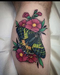 a colorful butterfly with flowers on it's thigh is shown in this tattoo design