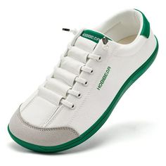 a white and green tennis shoe with laces on the outstratched sole